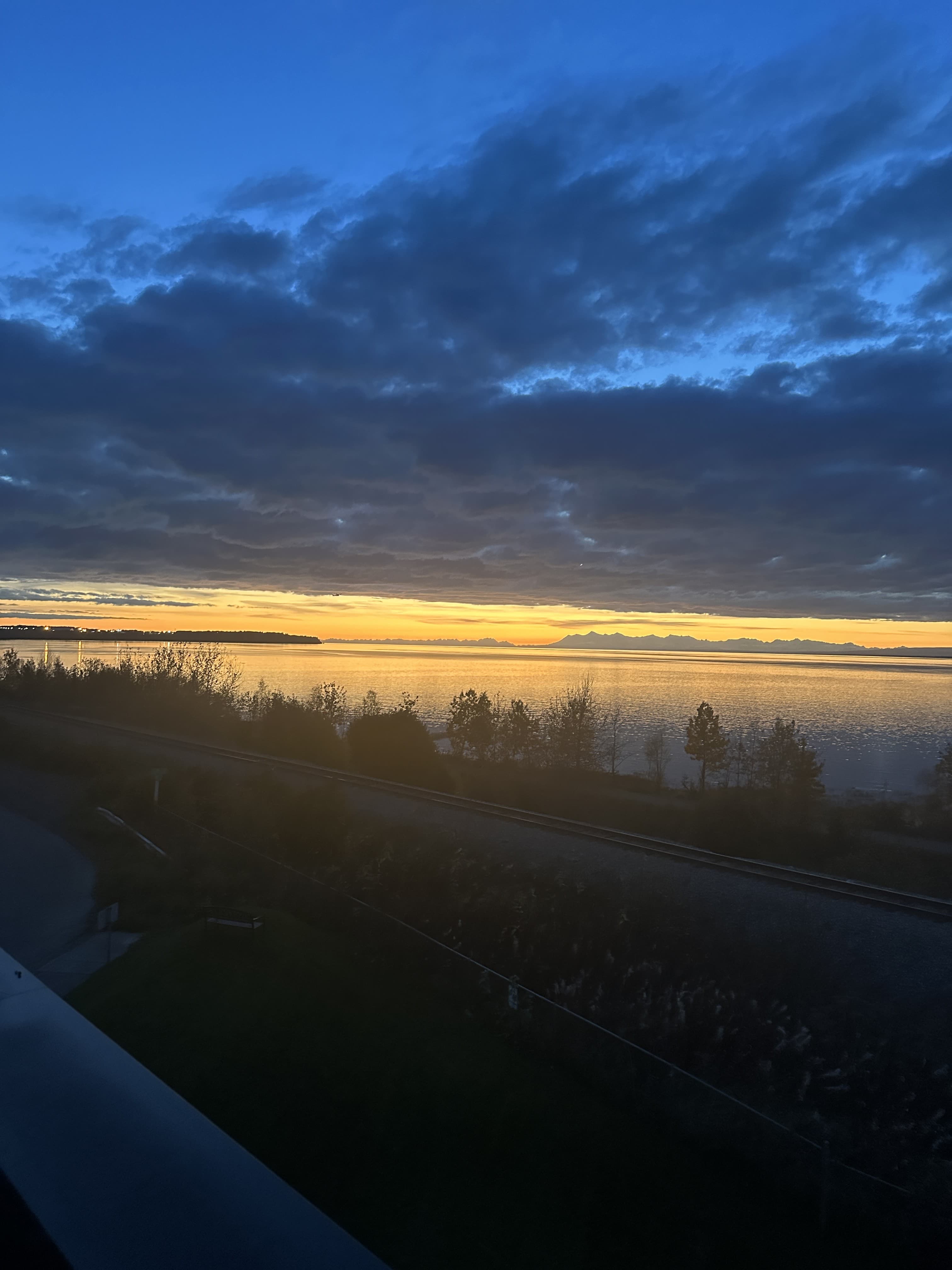 Midnight sun glowing gold over Cook Inlet and the Alaska Range, seen from Bootleggers Landing